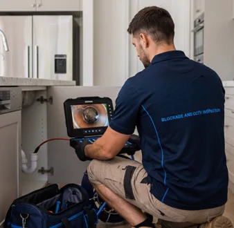 Plumber clearing a blocked toilet in a Beaconsfield bathroom